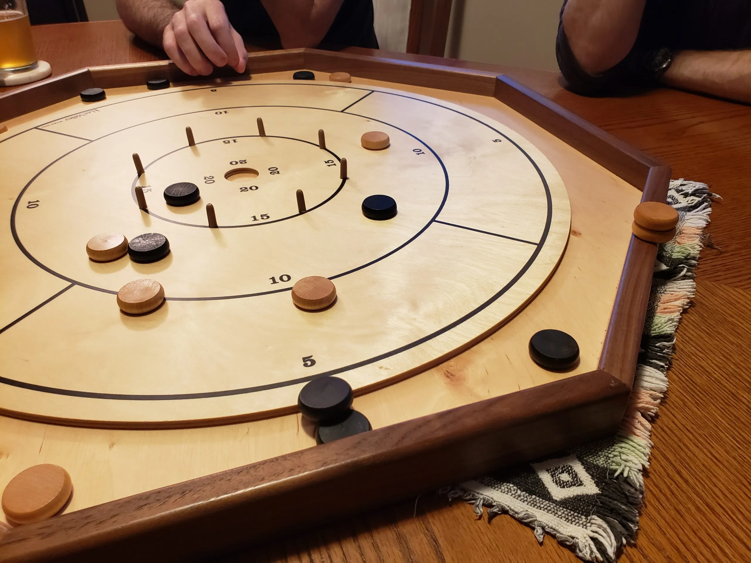 A wooden Crokinole board with discs mid-game